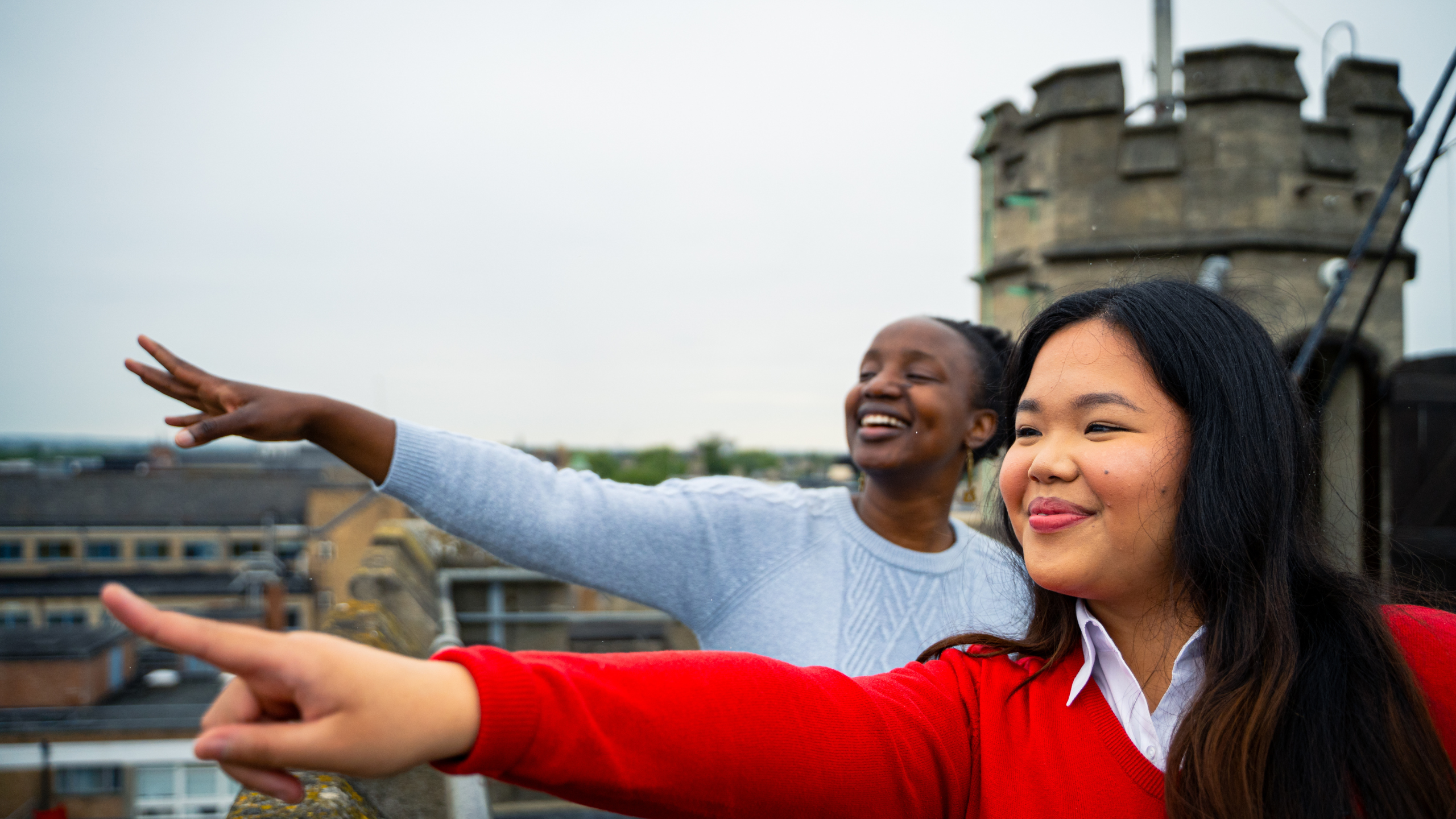 Two people pointing at the view from the top of Carfax Tower in Oxford.